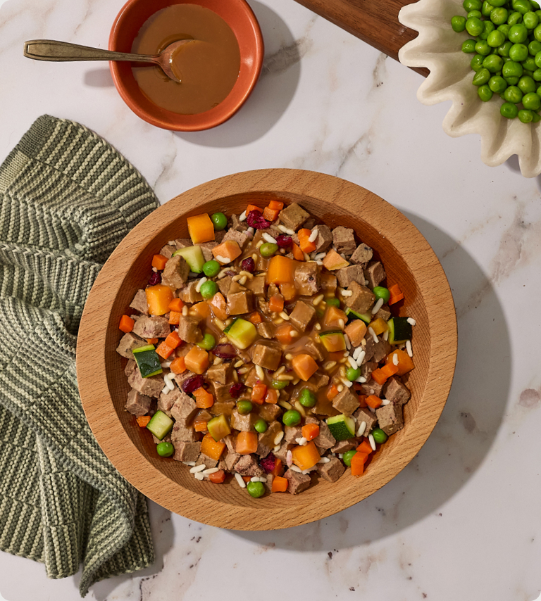 Chicken-Glazed Beef bowl: fresh dog food with beef, zucchini, carrots and peas in a wooden bowl
